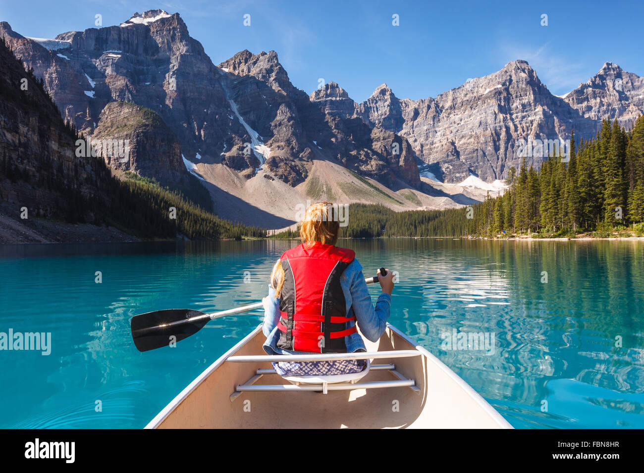 Una giovane donna canoa ai Moraine Lake, il Parco Nazionale di Banff, Alberta, Canada, America (Canada Montagne Rocciose). Foto Stock