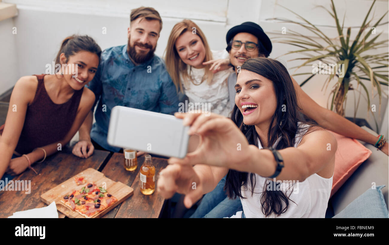 Gruppo di amici prendendo selfie su uno smart phone. Giovani uomini e donne che prendono un autoritratto sul telefono cellulare. I giovani su rooft Foto Stock