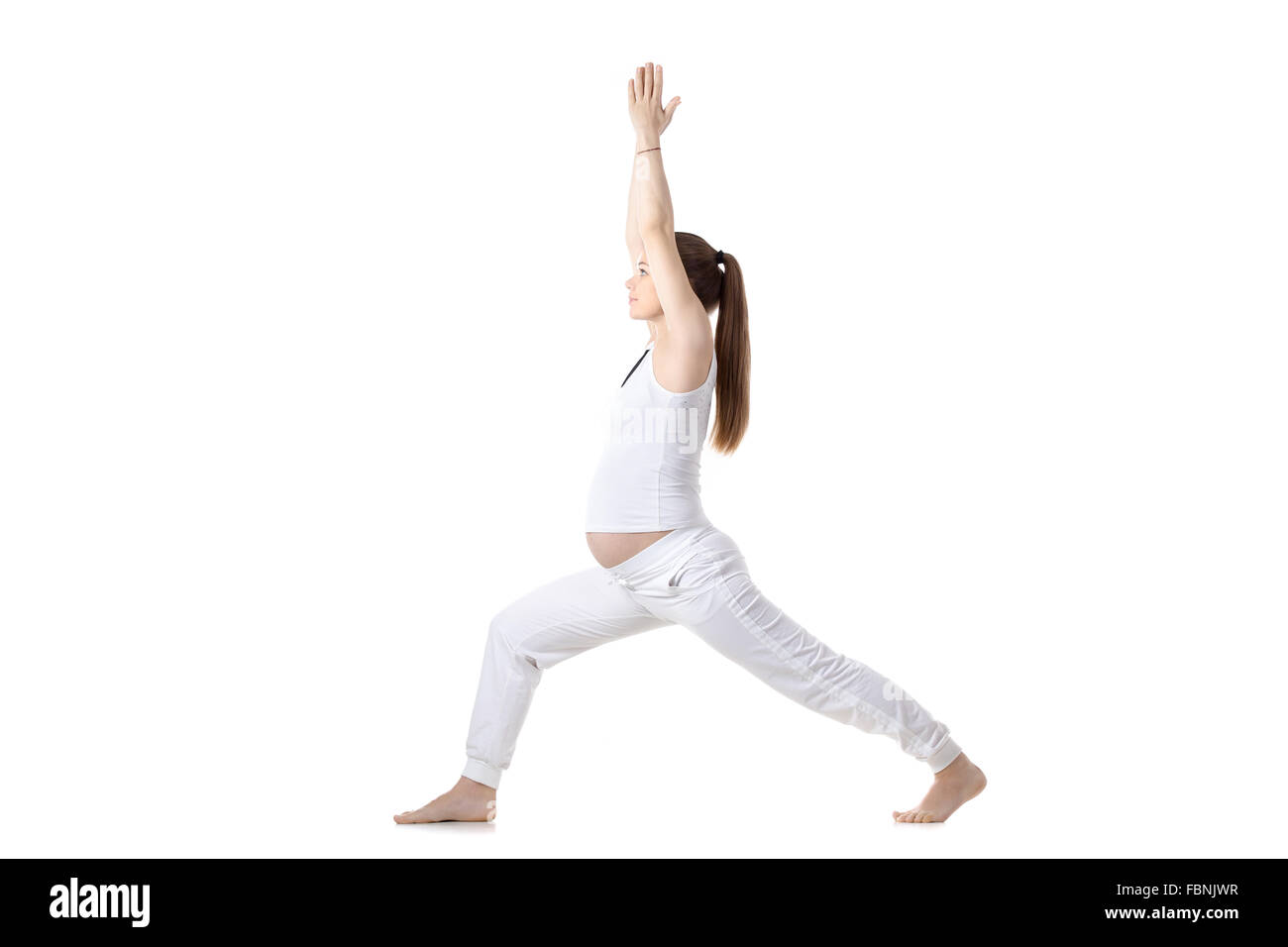 A piena lunghezza Ritratto di giovane incinta modello di fitness in bianco sportswear fare yoga o pilates formazione permanente, nella posizione del Guerriero I Foto Stock