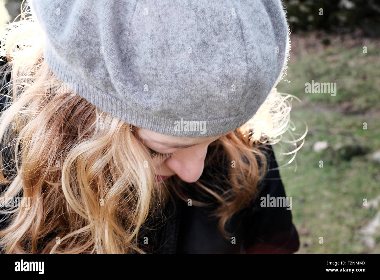 Donna bionda in grigio cappello di lana guardando verso il basso Foto stock  - Alamy