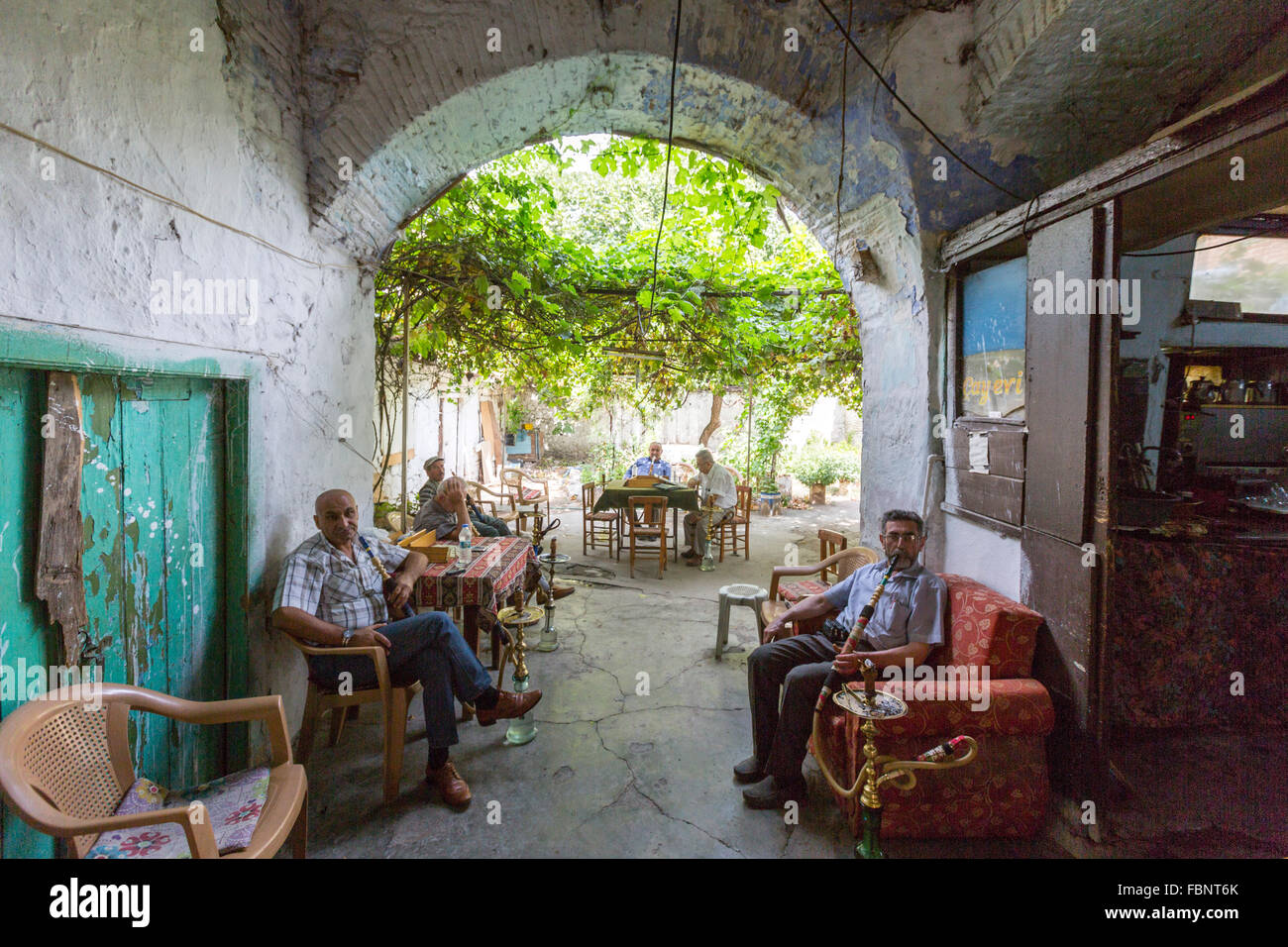 Il vecchio uomo seduto in un bar situato nel cortile Cukurhan, fumare una Turchia acqua shisha tubo di fumo in Bergama Bazaar Foto Stock