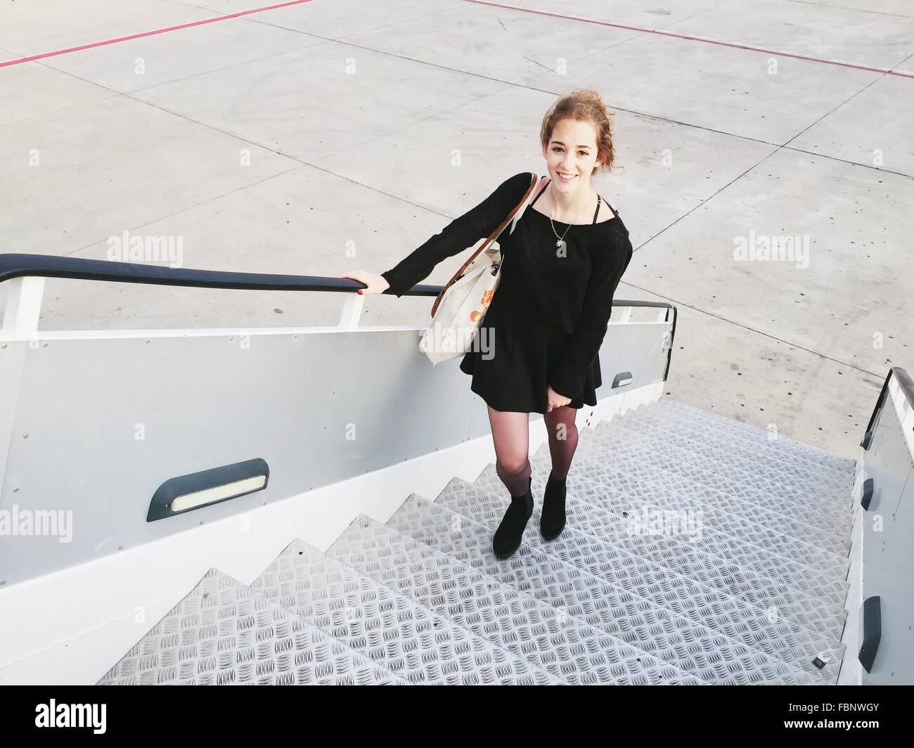 Elevato angolo di vista ritratto di donna in piedi sulla scalinata del velivolo in pista Foto Stock
