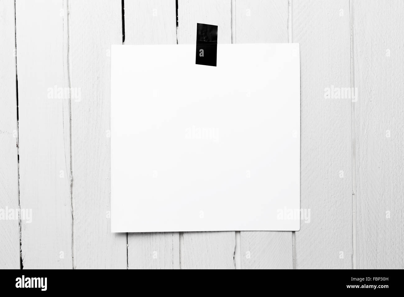 Schermata bianca vuota poster appeso su un nastro bianco sul tavolato in legno parete. Foto Stock