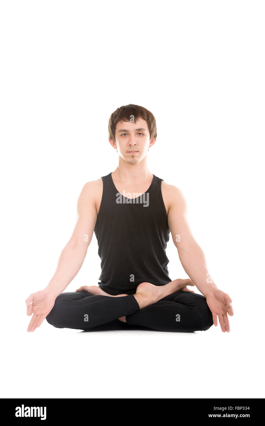 La meditazione, sportivo serena giovane uomo in seduta con le gambe incrociate lotus Yoga asana Padmasana con le dita in yogic gesto Chin Mudra Foto Stock