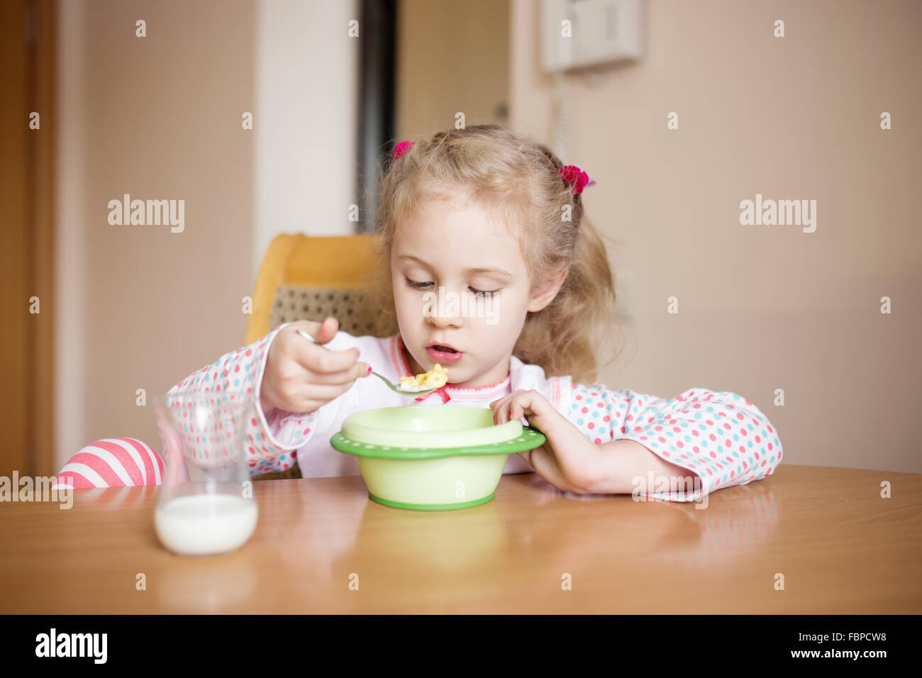 Bambina con colazione a casa. Baffi di latte Foto Stock