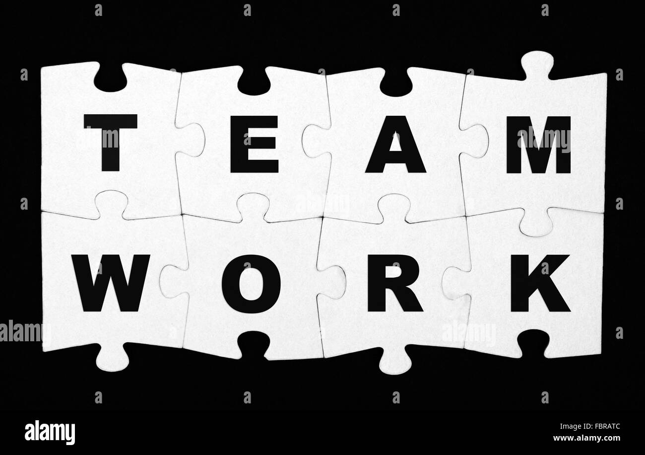 Il lavoro di squadra puzzle su sfondo nero Foto Stock
