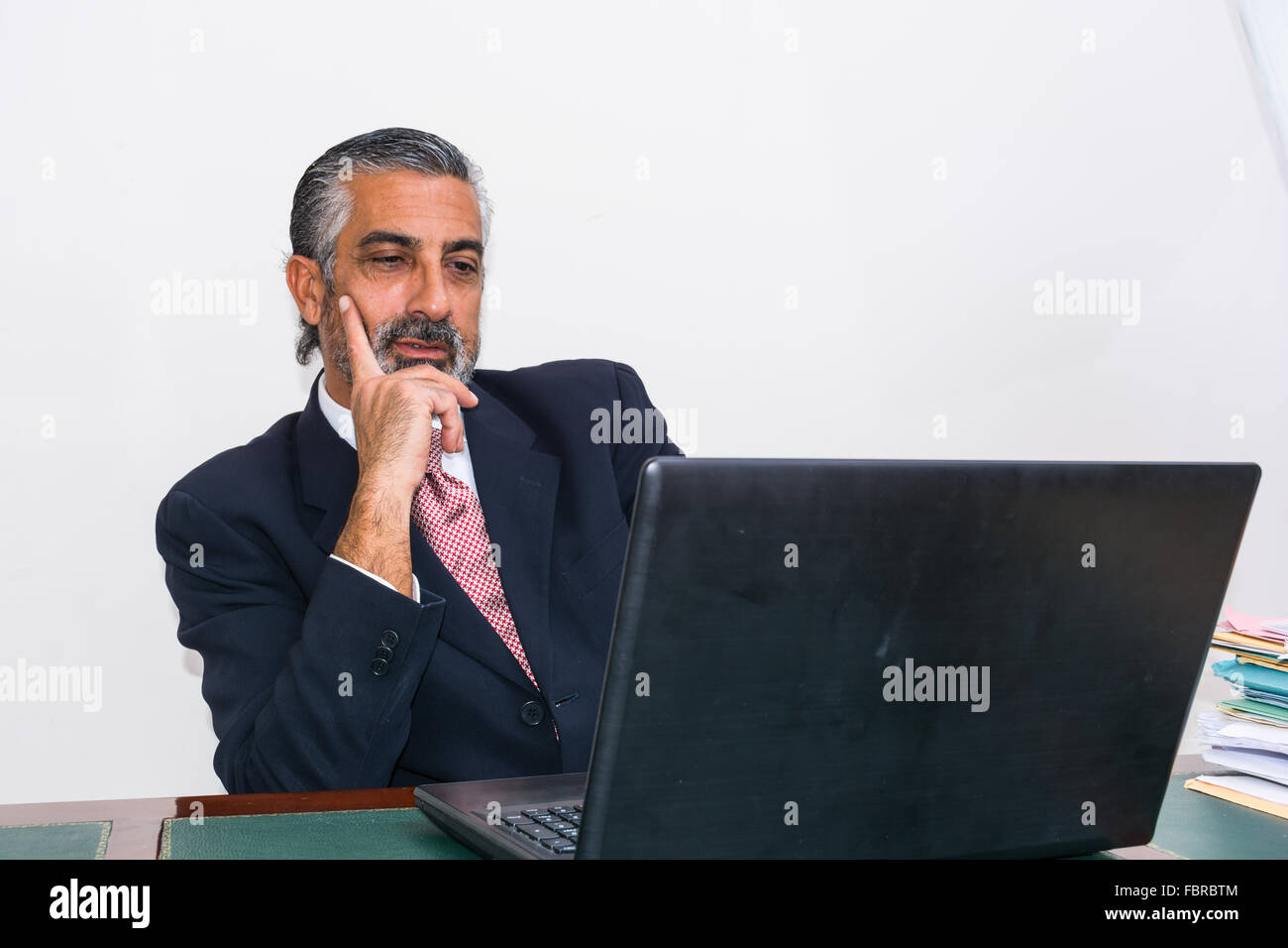 Imprenditore in un vestito e cravatta, nel suo studio. Alla scrivania, utilizzando il PC. Foto Stock