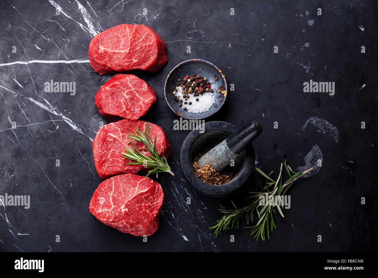 Crudo fresco marmo bistecca di carne e condimenti scuro su sfondo marmo Foto Stock