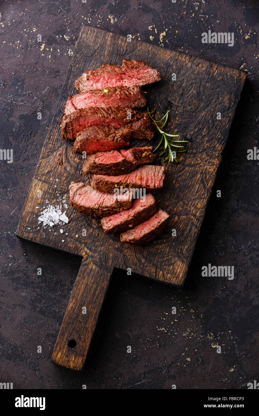 Fette di mezzo raro grigliate di carne di manzo sul tagliere di legno Foto Stock