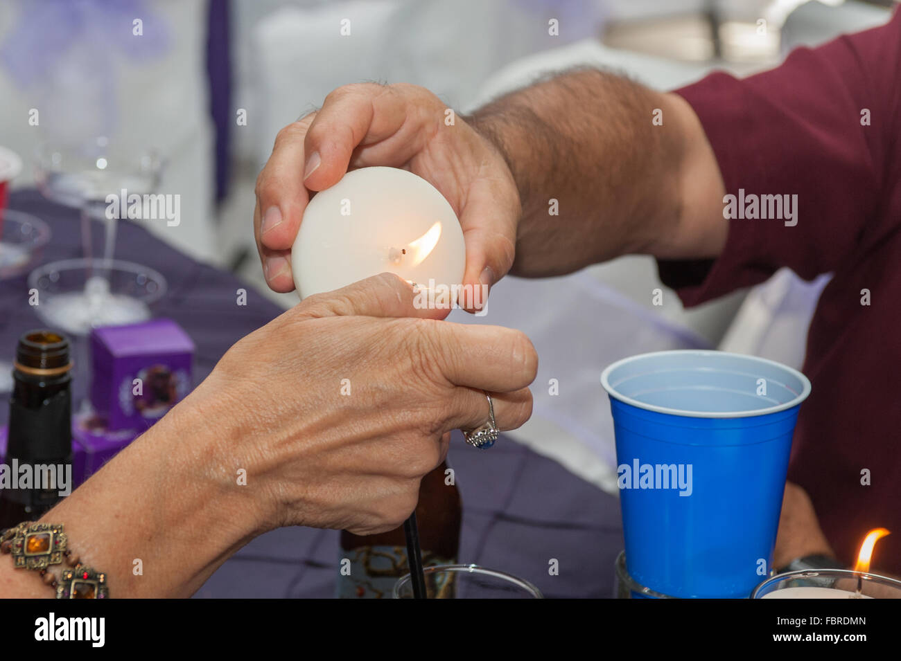 Aiutando le mani accendere una candela. Foto Stock