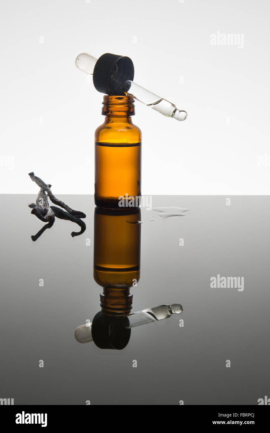 La vaniglia olio essenziale nel flacone color ambra con baccelli di vaniglia con contagocce Foto Stock