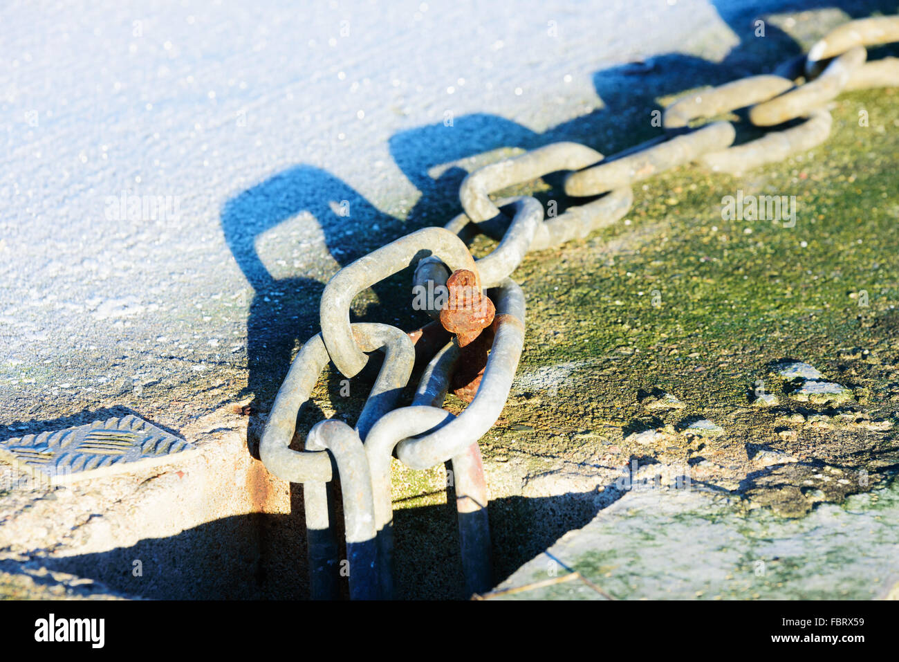 In prossimità di una catena di metallo trovato presso un porto turistico alla fine di un pontile galleggiante. Frost accanto al link. Freddezza sparkle dal ghiaccio. Foto Stock
