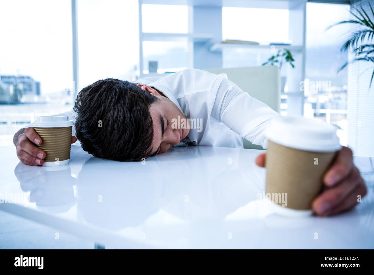Sleeping imprenditore tenendo il calice di caffè Foto Stock