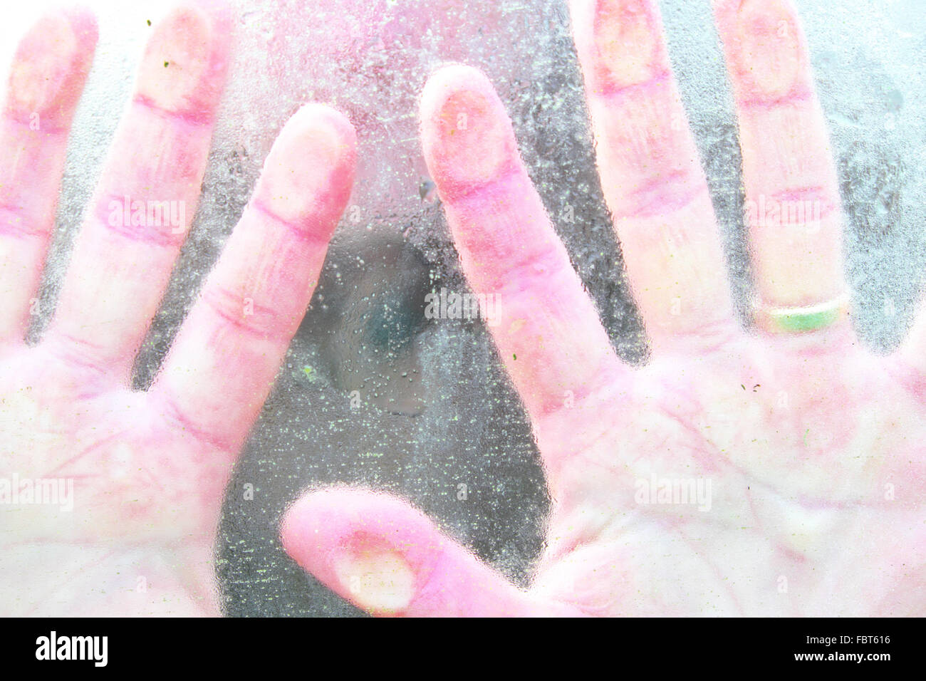A basse temperature le mani fredde premuto contro una finestra a freddo Foto Stock