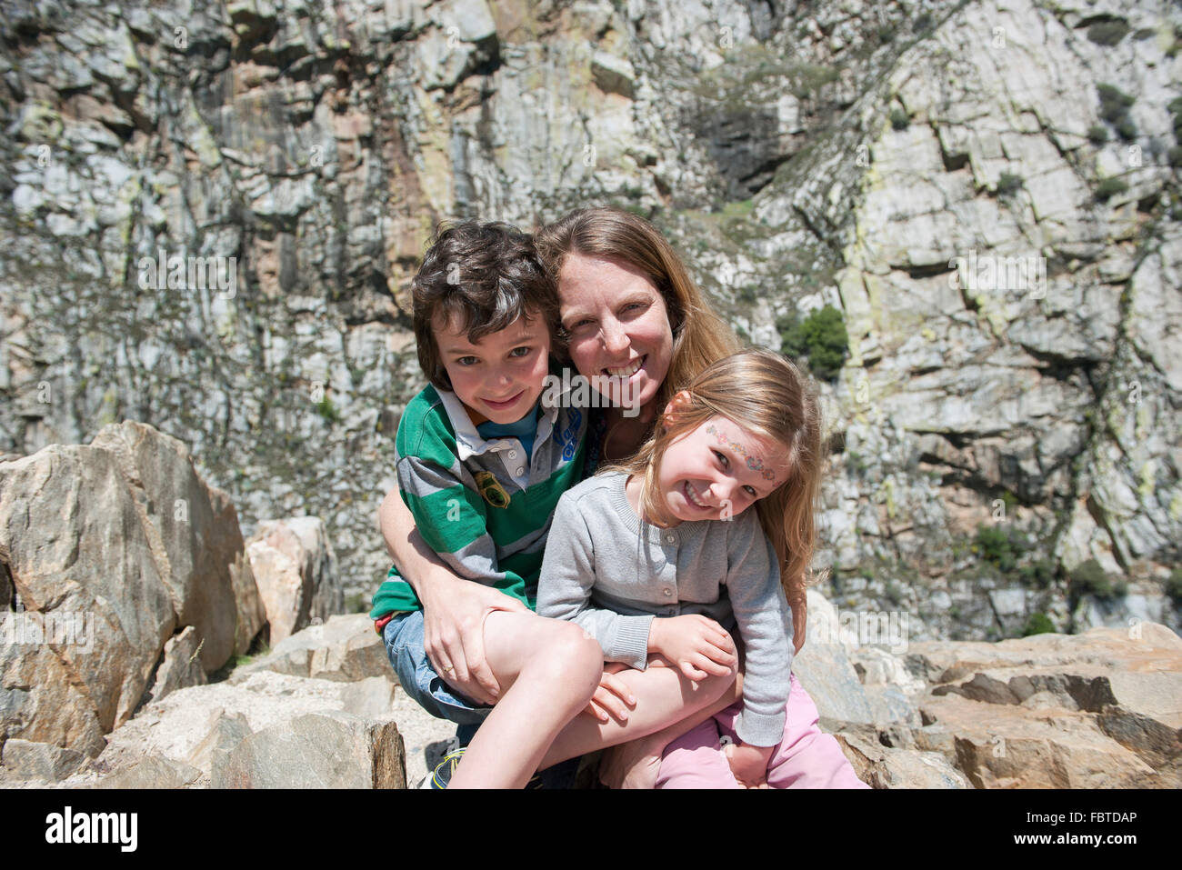 Madre e bambini seduti sulla formazione di roccia, ritratto Foto Stock