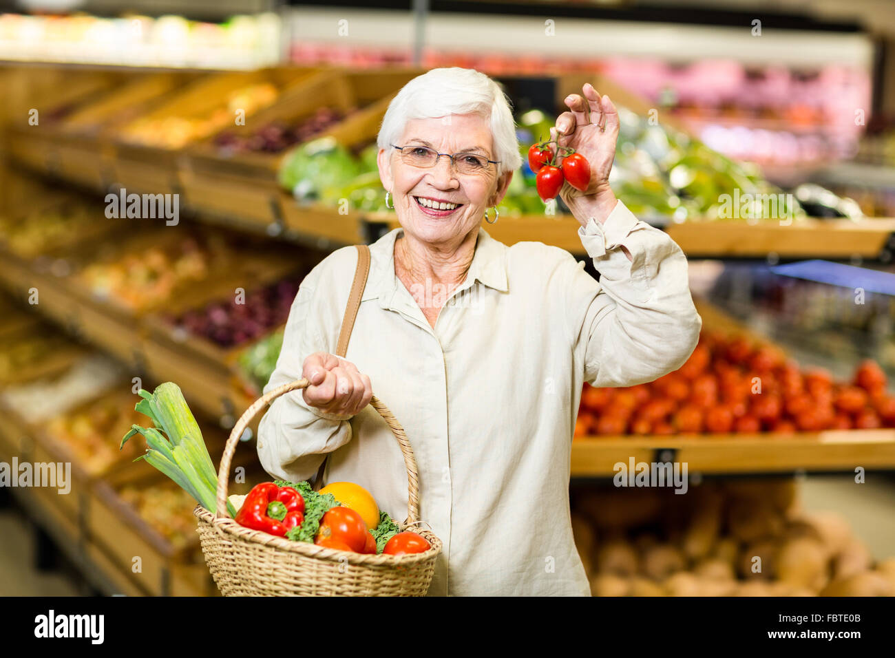 Senior donna cestello di contenimento e pomodorini Foto Stock