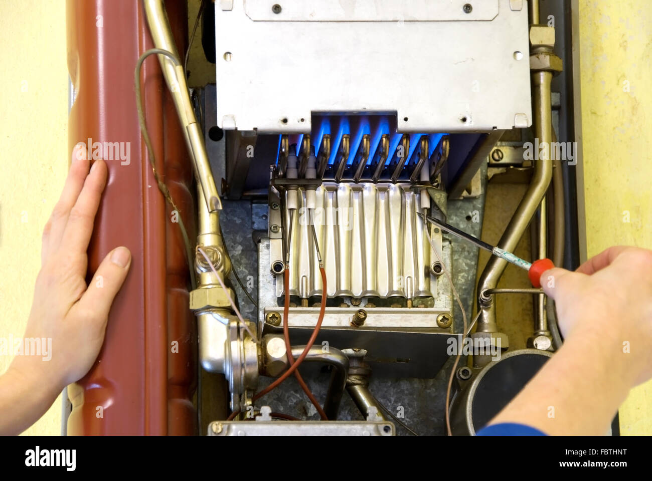 Le mani di un idraulico riparazione di un riscaldamento a gas Foto Stock