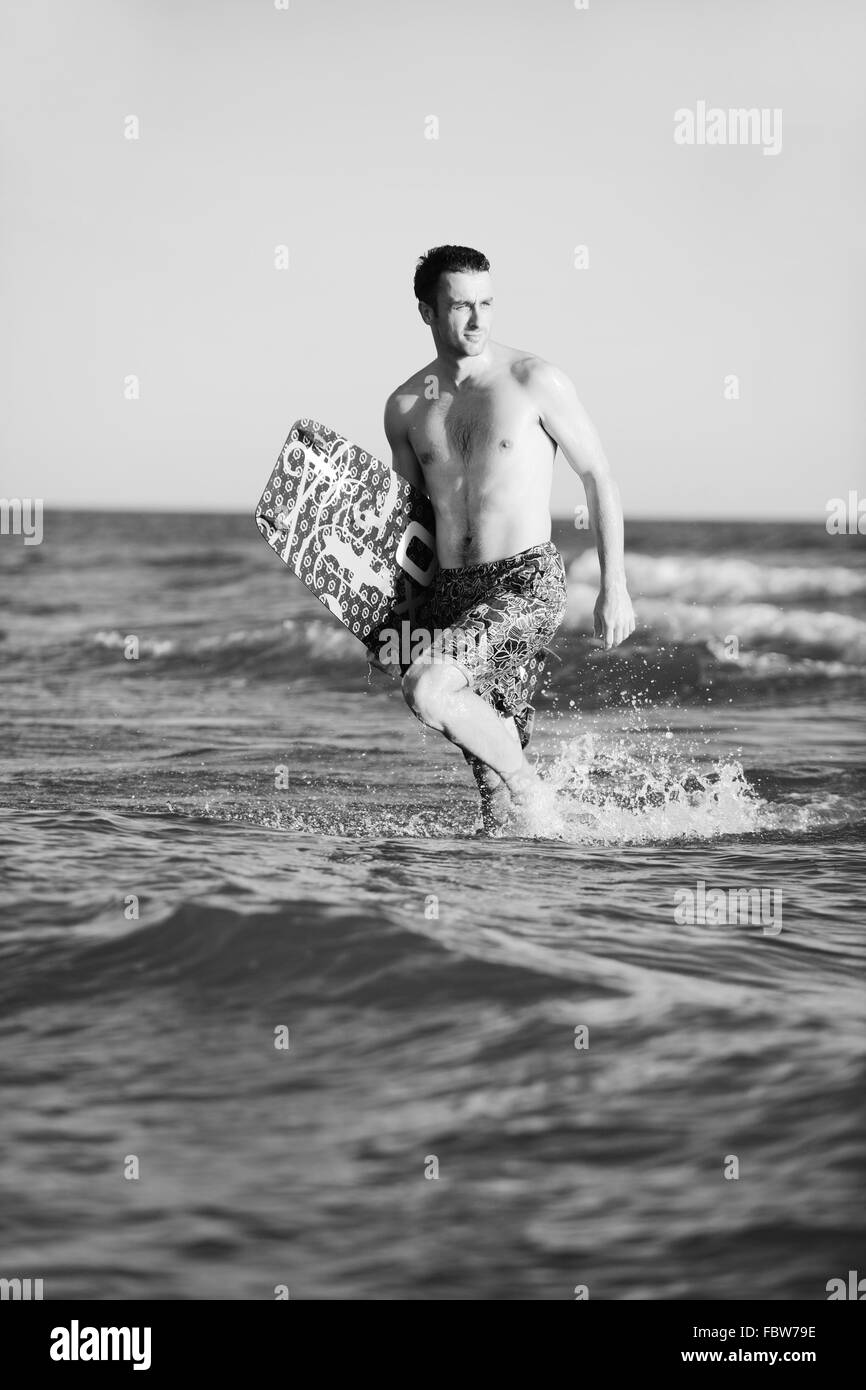 Ritratto di un giovane uomo kitsurf presso la spiaggia sul tramonto Foto Stock