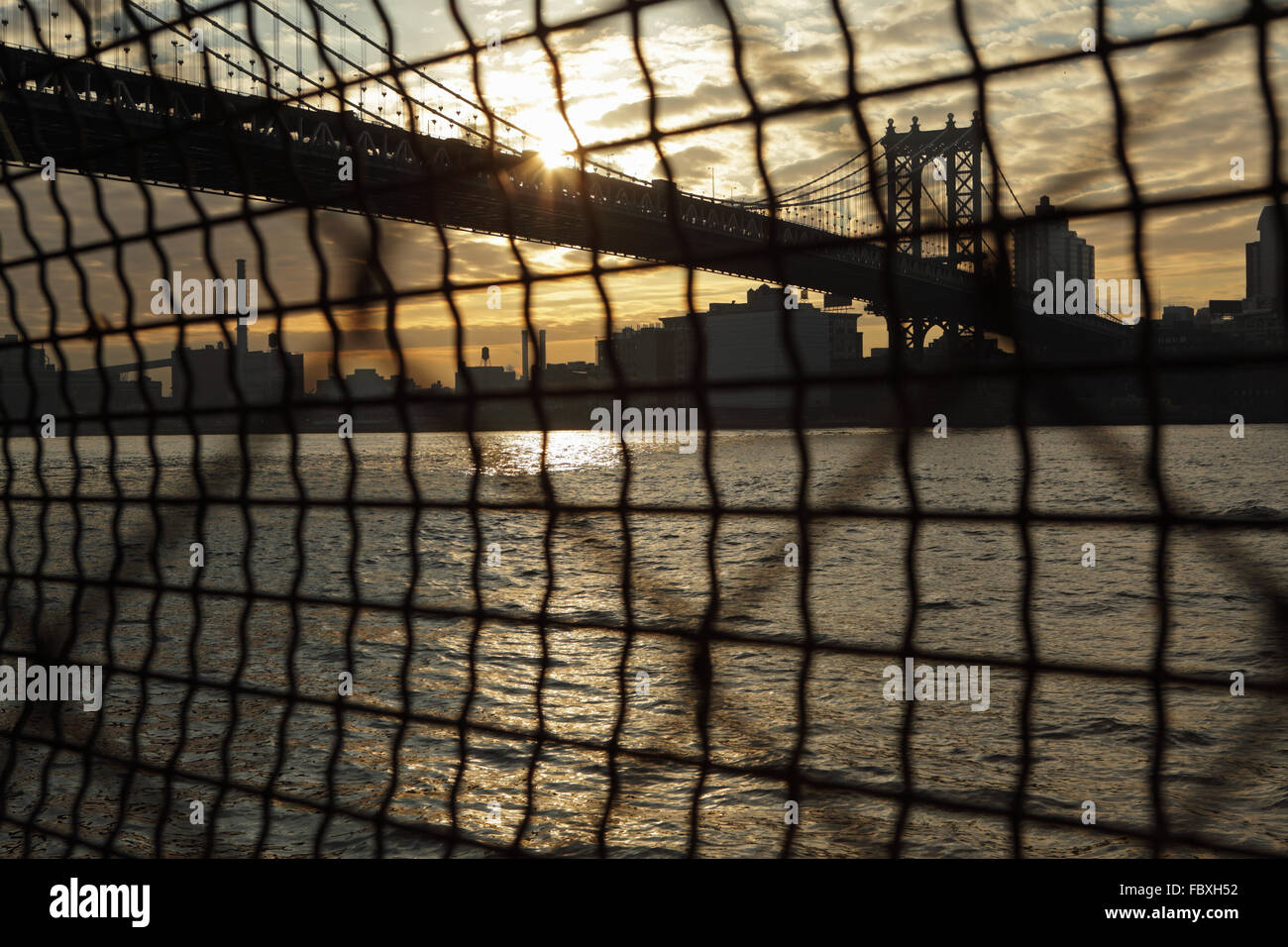 Distorta visione industriale di Manhattan Bridge waterfront sunrise New York City attraverso un recinto di filo Foto Stock