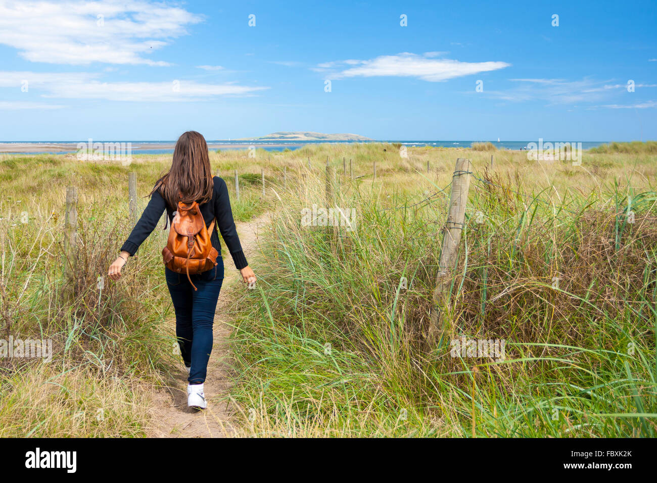 Giovane donna a piedi lungo il sentiero vicino alla spiaggia Foto Stock