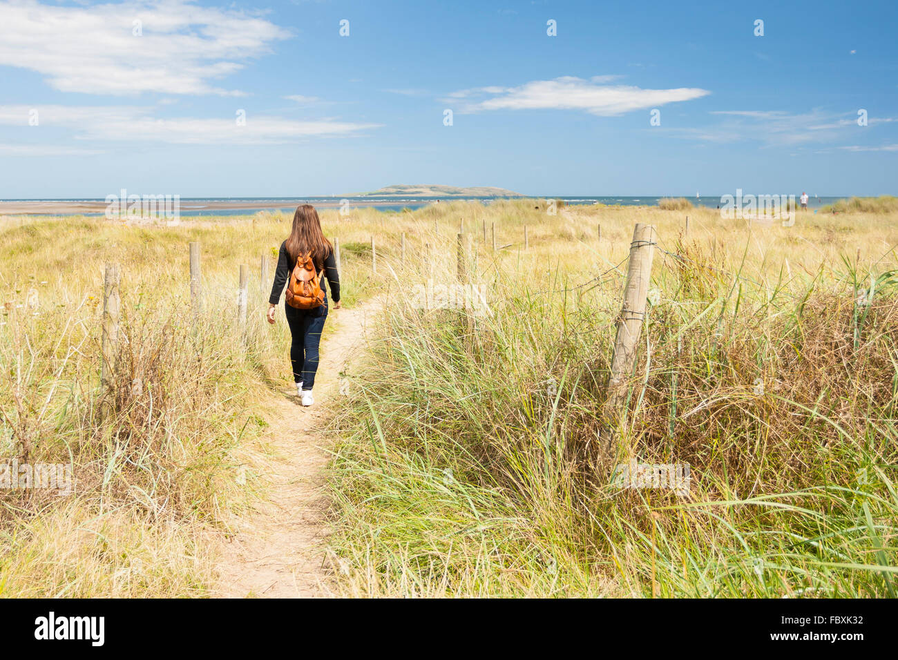 Giovane donna a piedi lungo il sentiero vicino alla spiaggia Foto Stock