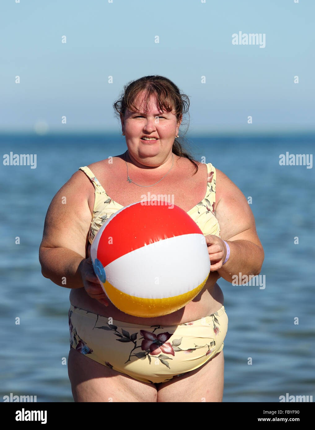 Il sovrappeso donna con palla sulla spiaggia Foto Stock