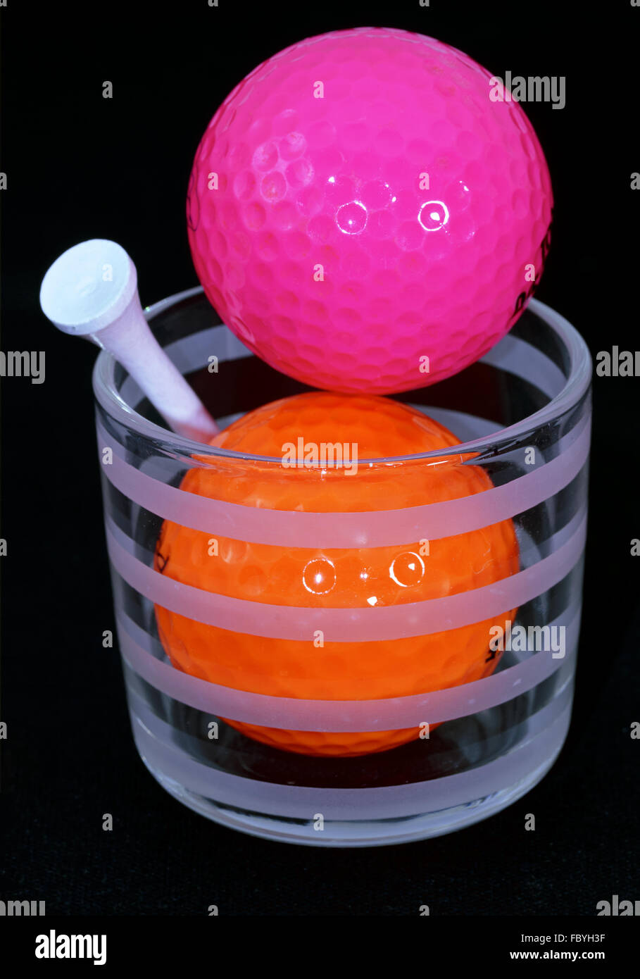 Arancione e viola palline da golf con raccordo a T bianco Foto Stock