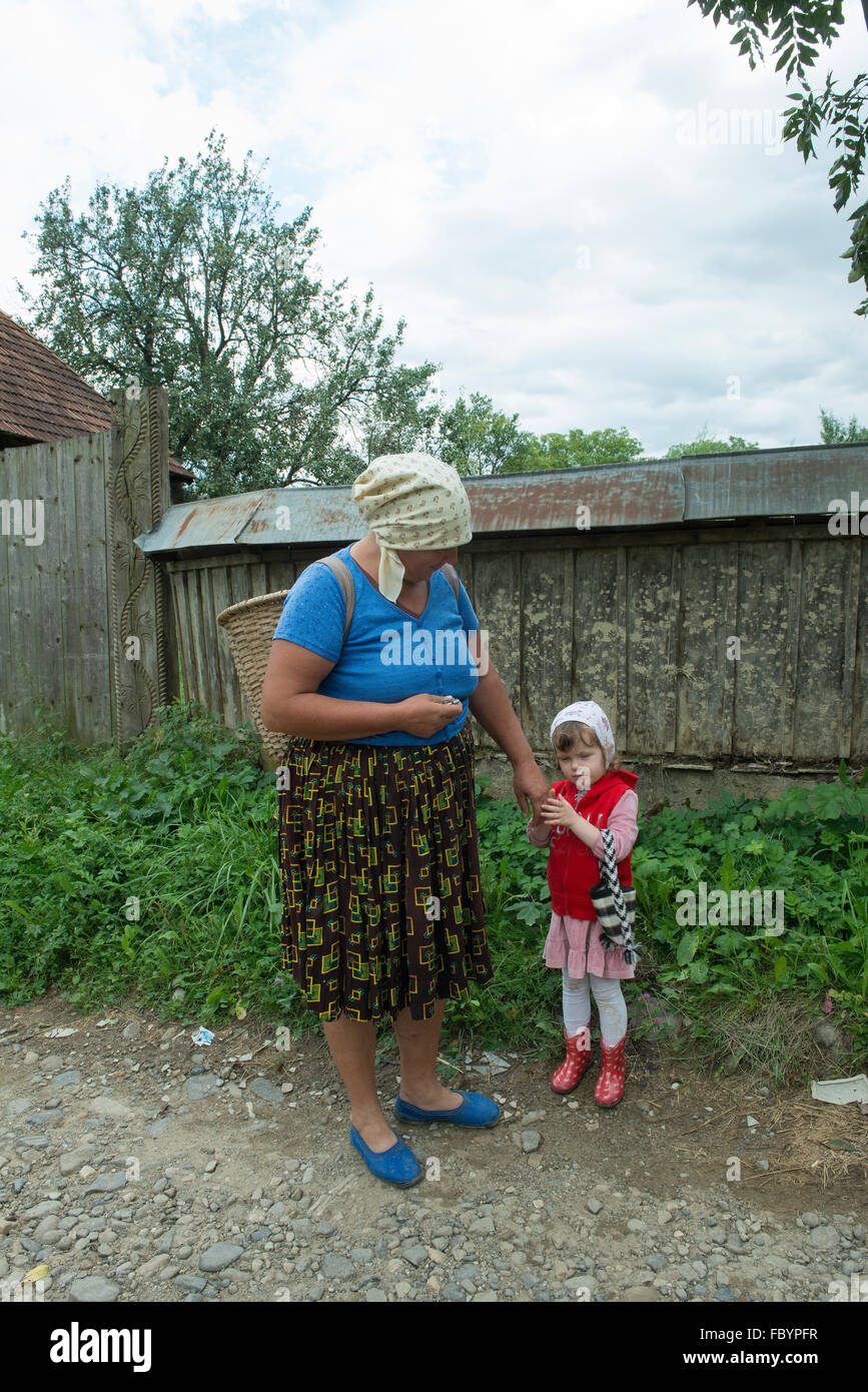 Donna anziana con la sua nipote sulla strada in un villaggio nel distretto di Maramures, Romania Foto Stock