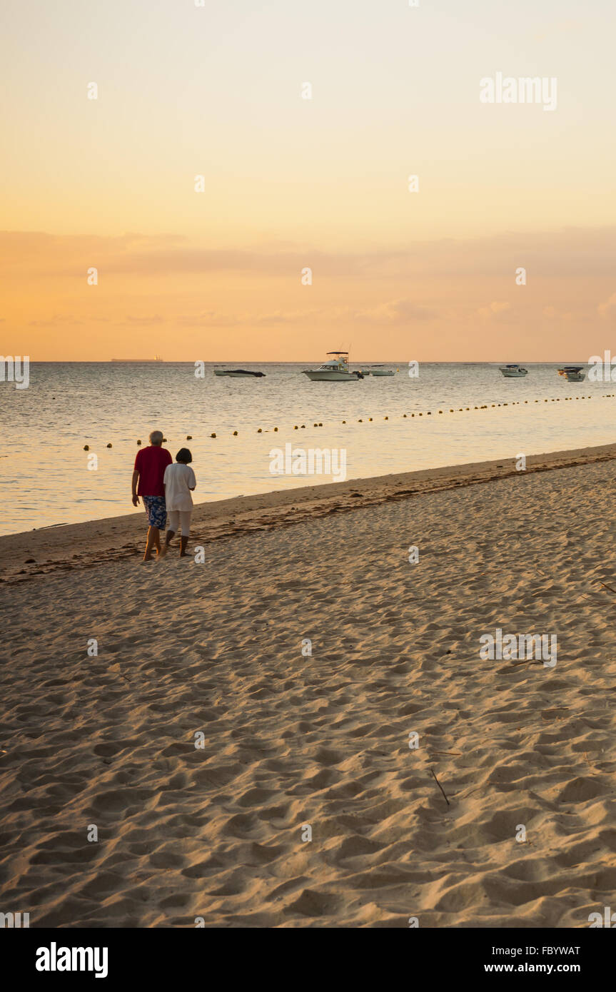 Un giovane a piedi lungo la spiaggia al tramonto Foto Stock