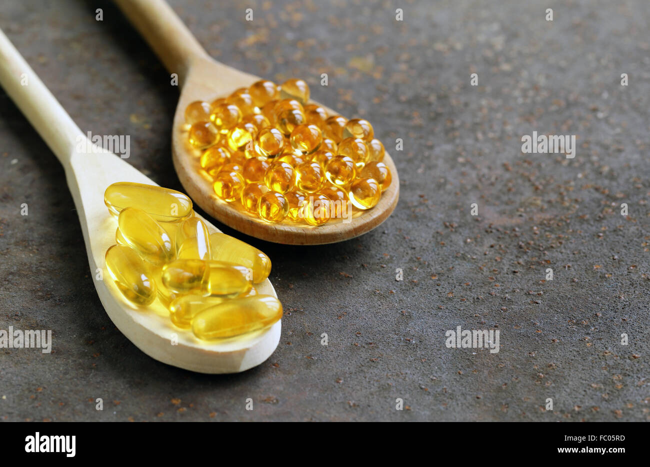 Integratore alimentare di olio di pesce capsule in un cucchiaio di legno - cibo sano Foto Stock