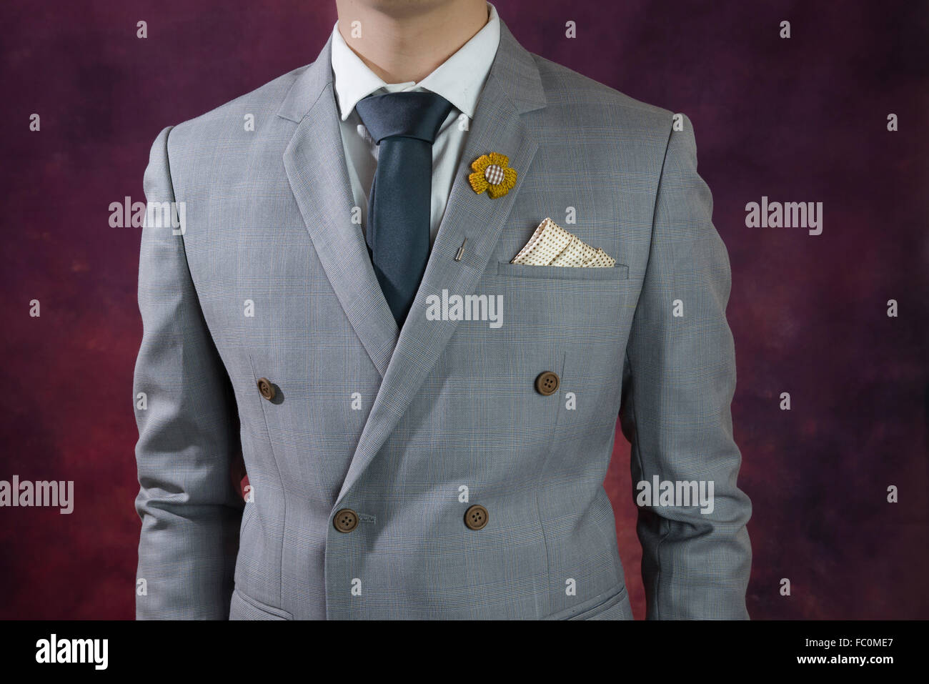 Uomo in doppio petto abito grigio, plaid texture, cravatta blu, fiore spilla, e la configurazione di punti fazzoletto, close up Foto Stock