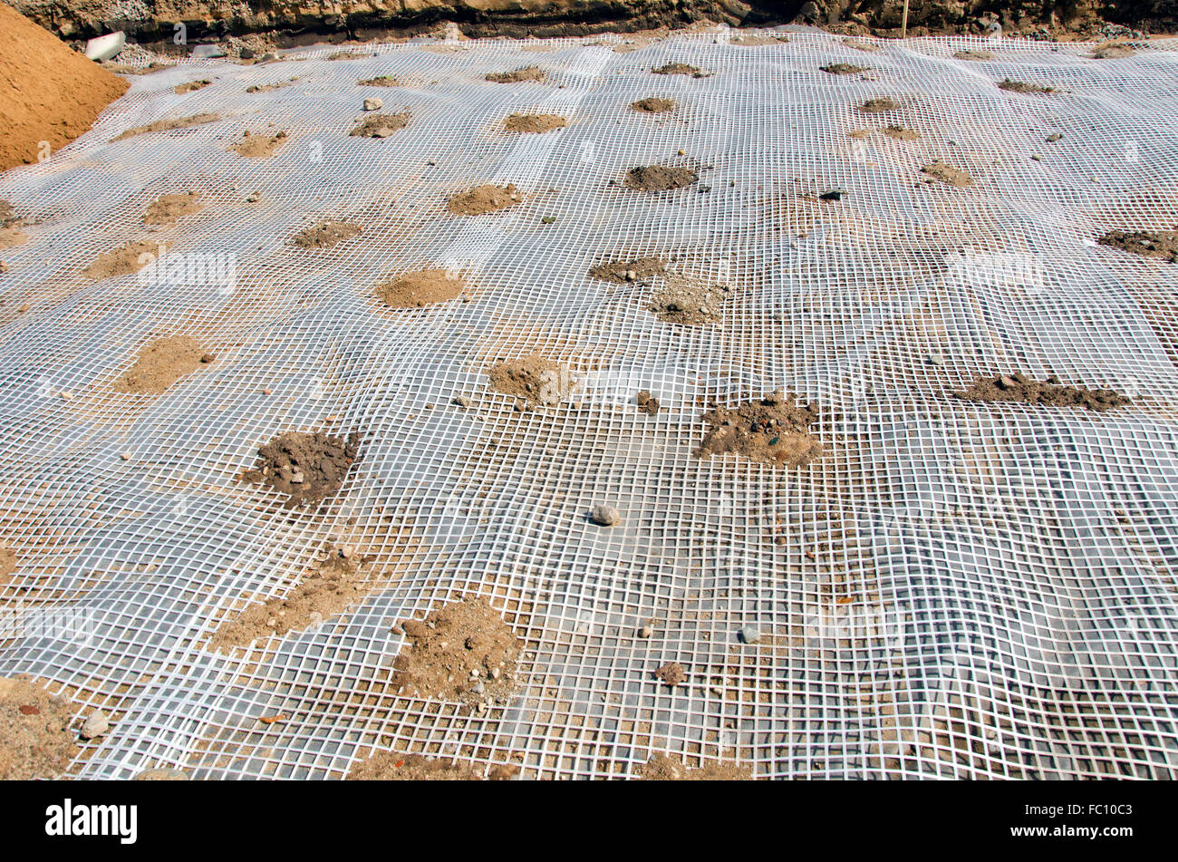 Preparazione per la posa di pavimentazione con rete di materiale plastico che copre il suolo Foto Stock