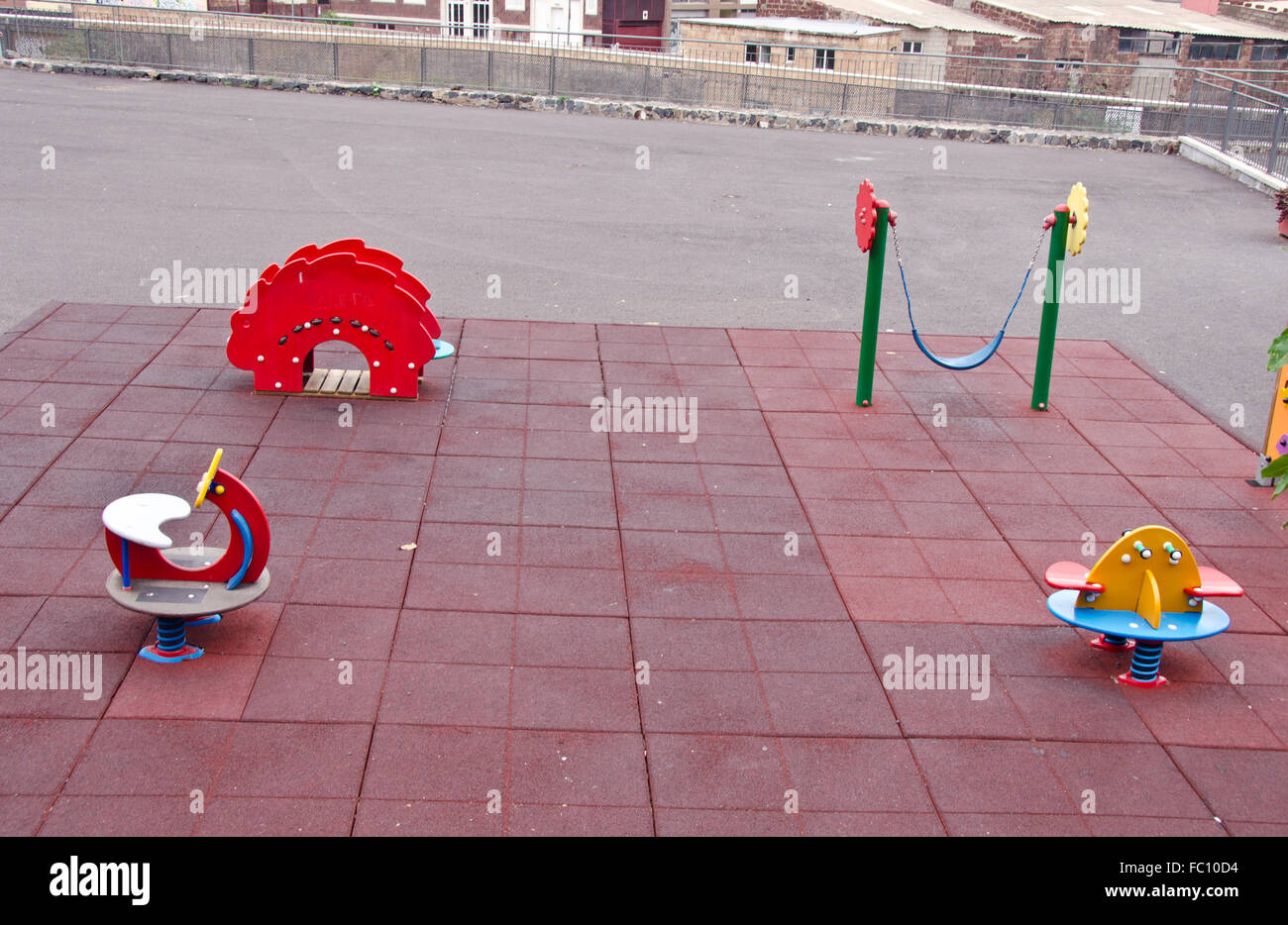 Area gioco per bambini con vari giocattoli e pavimentazione rosso in area urbana Foto Stock