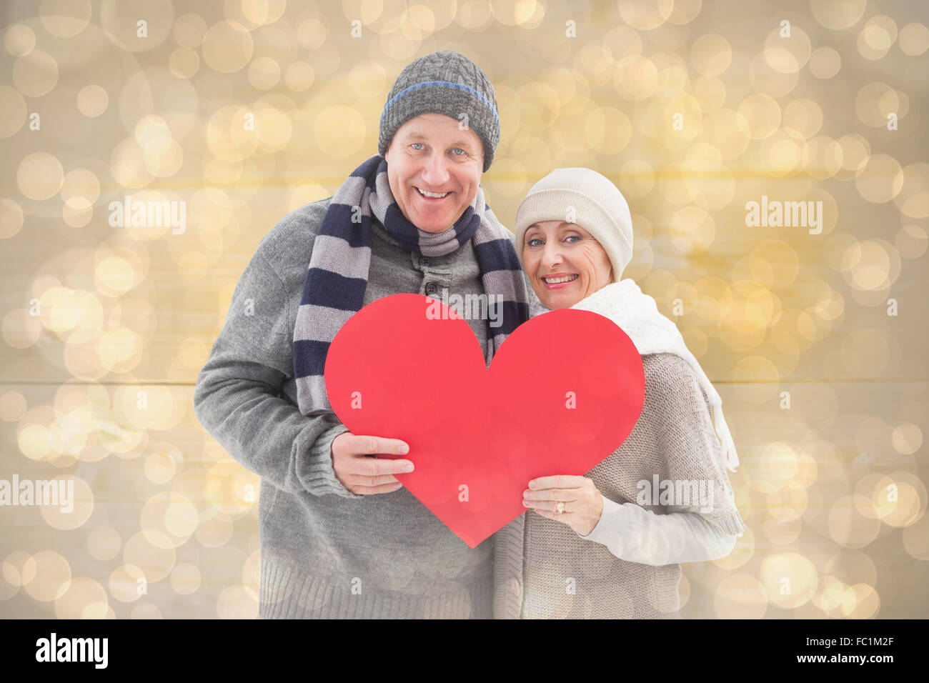 Immagine composita di felice coppia matura in inverno abiti azienda cuore rosso Foto Stock