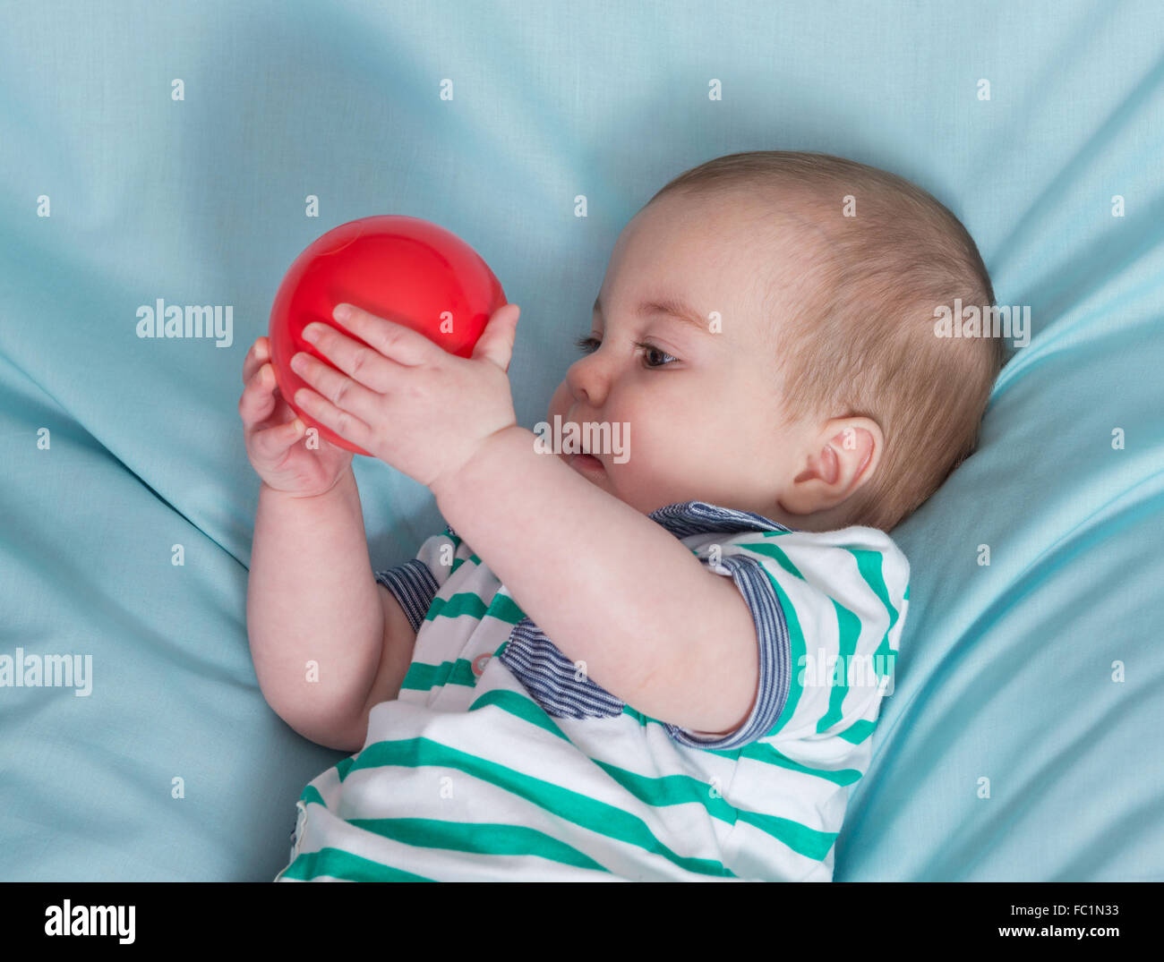 Adorabili happy baby boy con palla rossa su sfondo blu Foto Stock