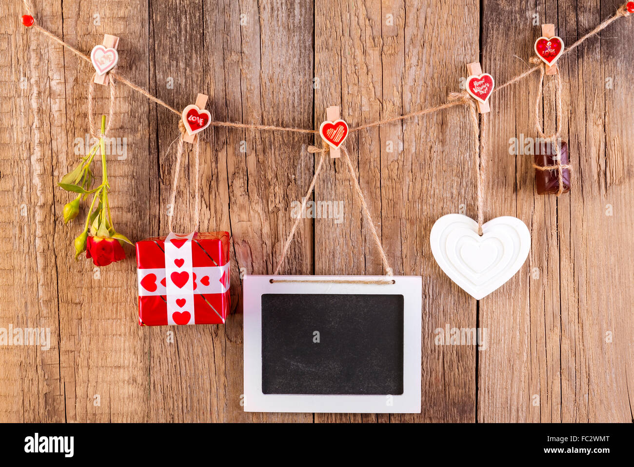 Red Rose con confezione regalo e una cornice bianca e cioccolato su sfondo di legno. Il concetto di amore. Foto Stock