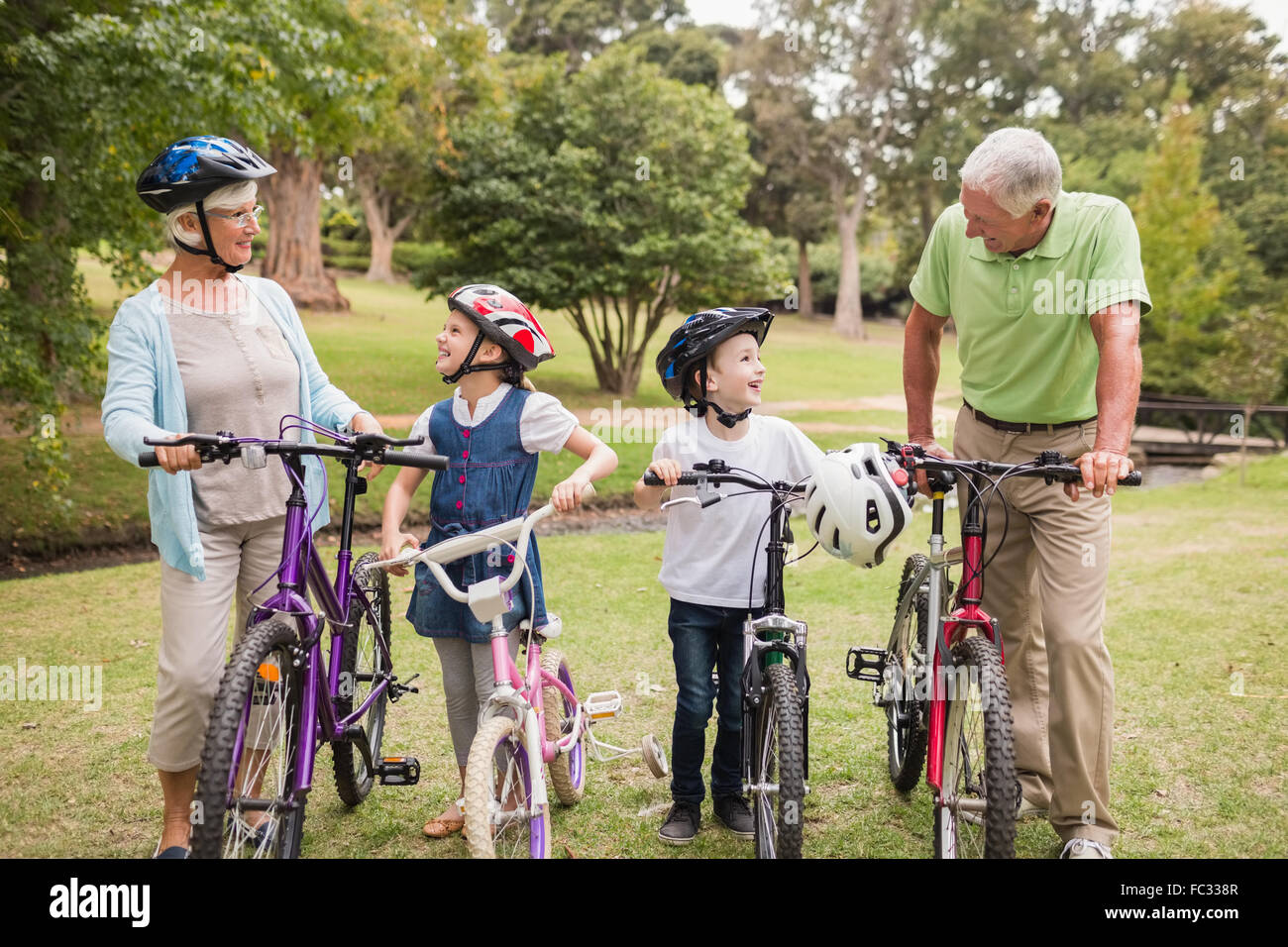 Felici i nonni con i loro nipoti in bicicletta Foto Stock