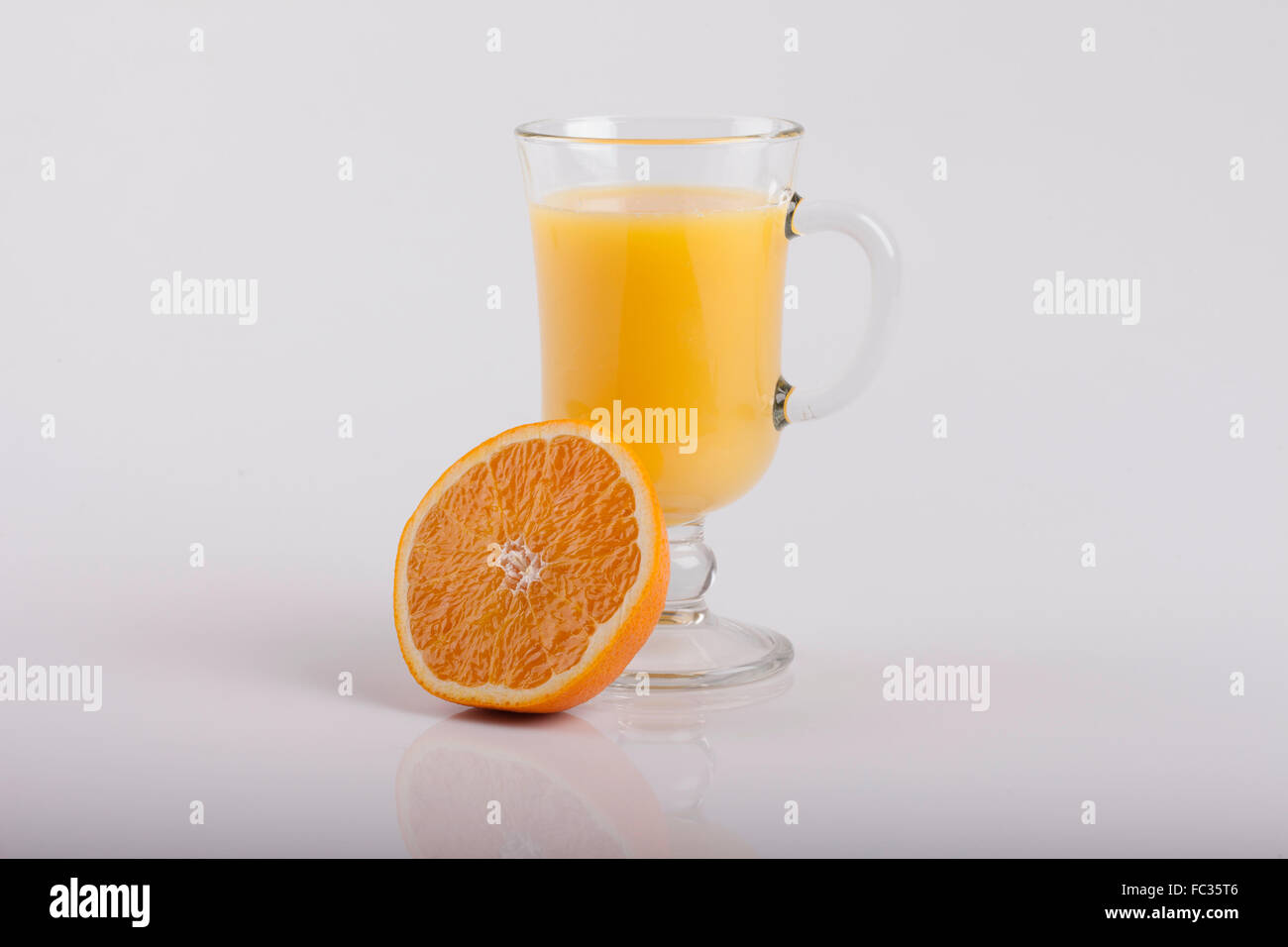 Bicchiere di succo di frutta e un'arancia a fette su bianco Foto Stock