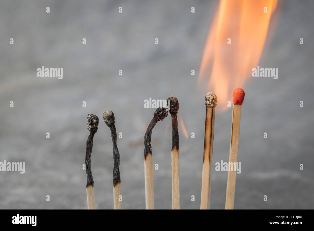 Una fila di corrispondenze a bruciare in una reazione a catena Foto Stock