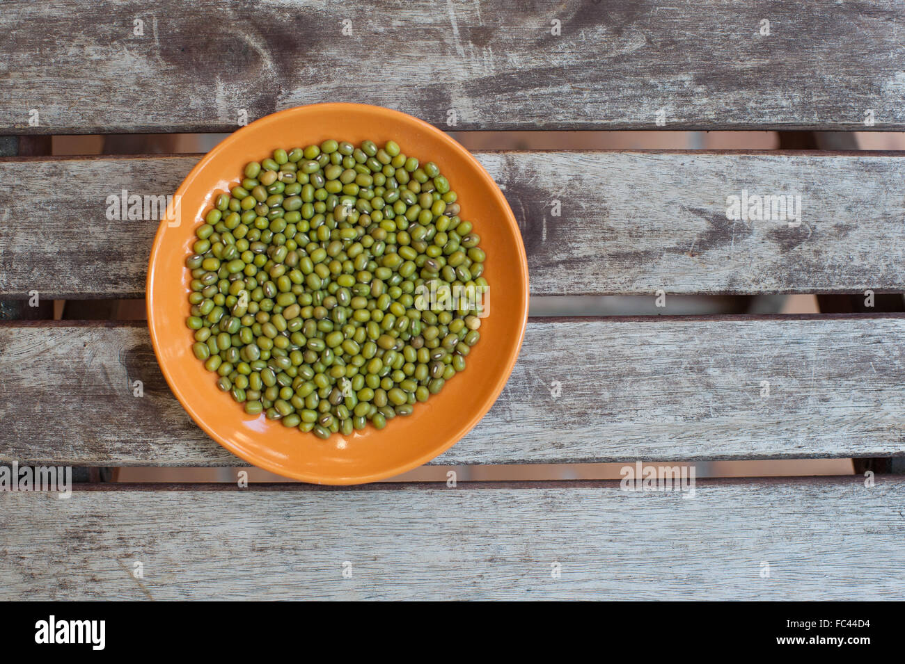 Orange Bowl con green Mung bean semi su sfondo di legno Foto Stock