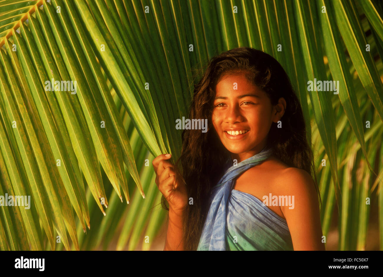 Ragazza polinesiano nella parte anteriore del green le fronde delle palme sulle Isole Cook nella luce del tramonto Foto Stock