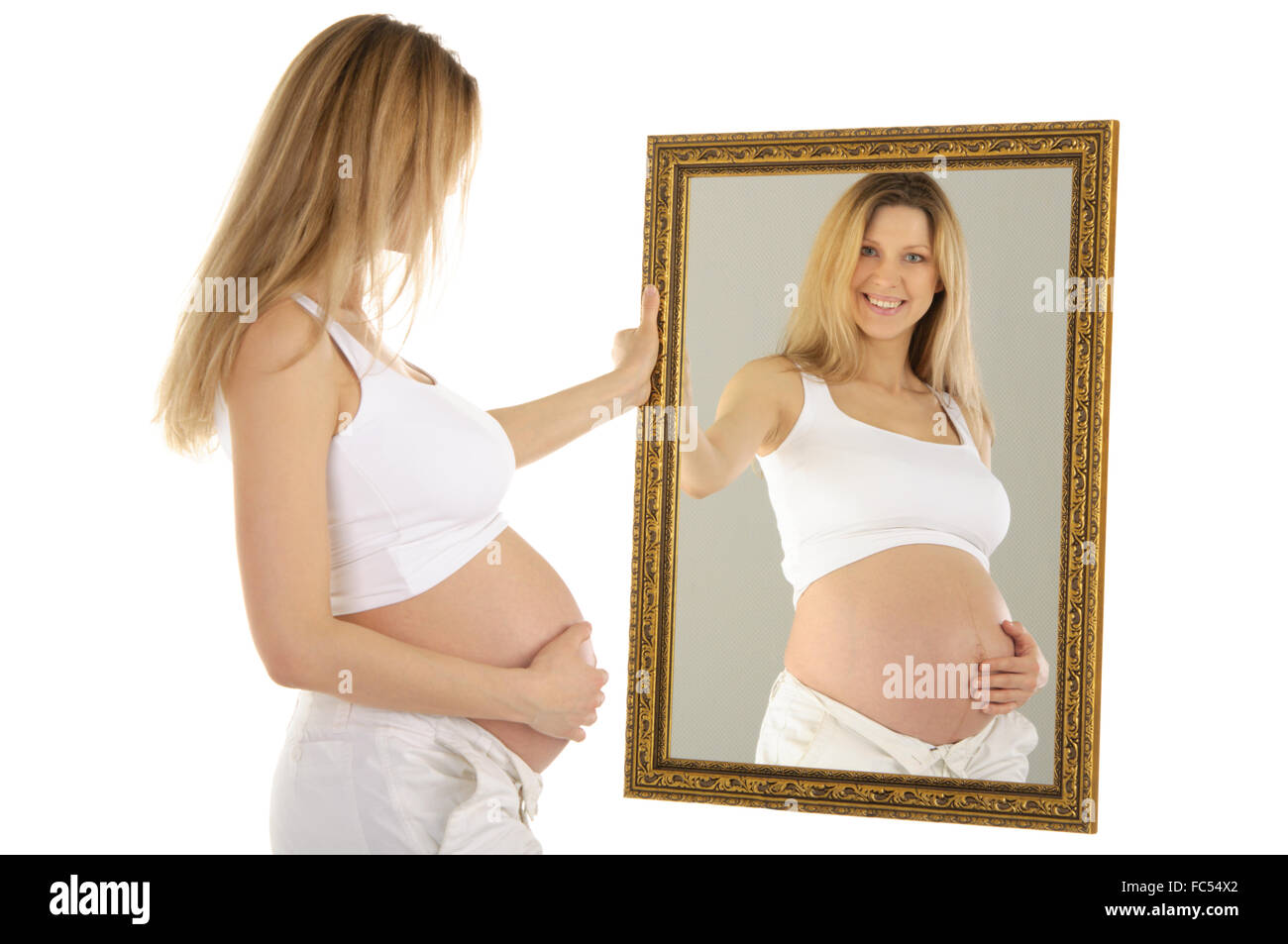 Donna incinta guarda nello specchio Foto Stock