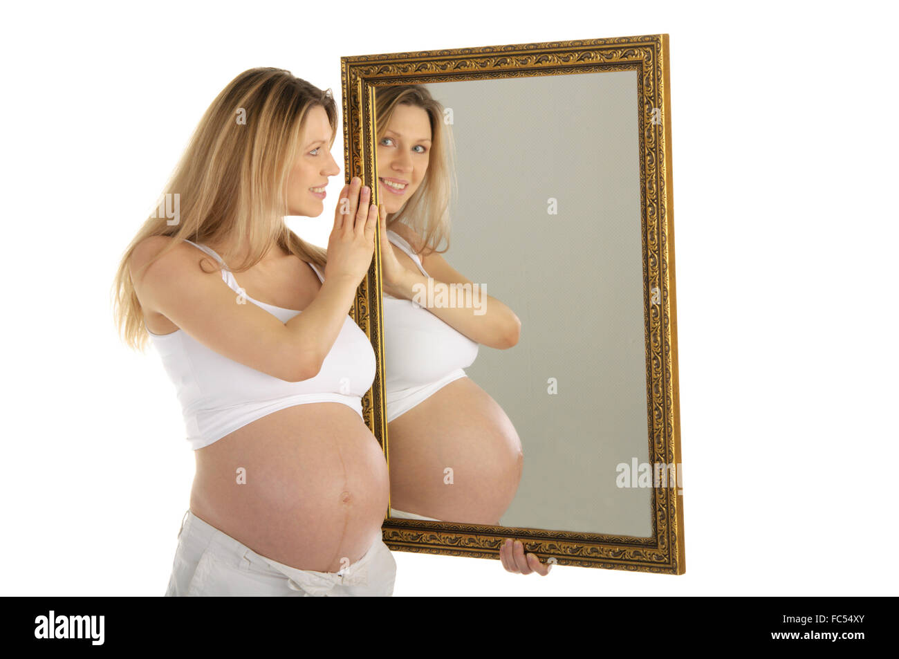 Donna incinta guarda nello specchio Foto Stock