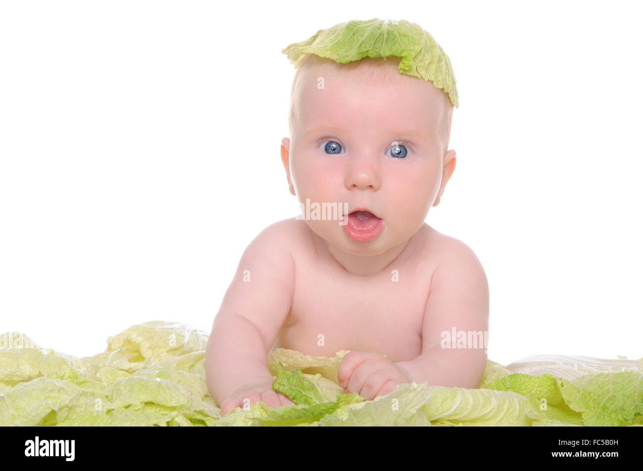 Piccolo bambino seduto tra le foglie di cavolo Foto Stock