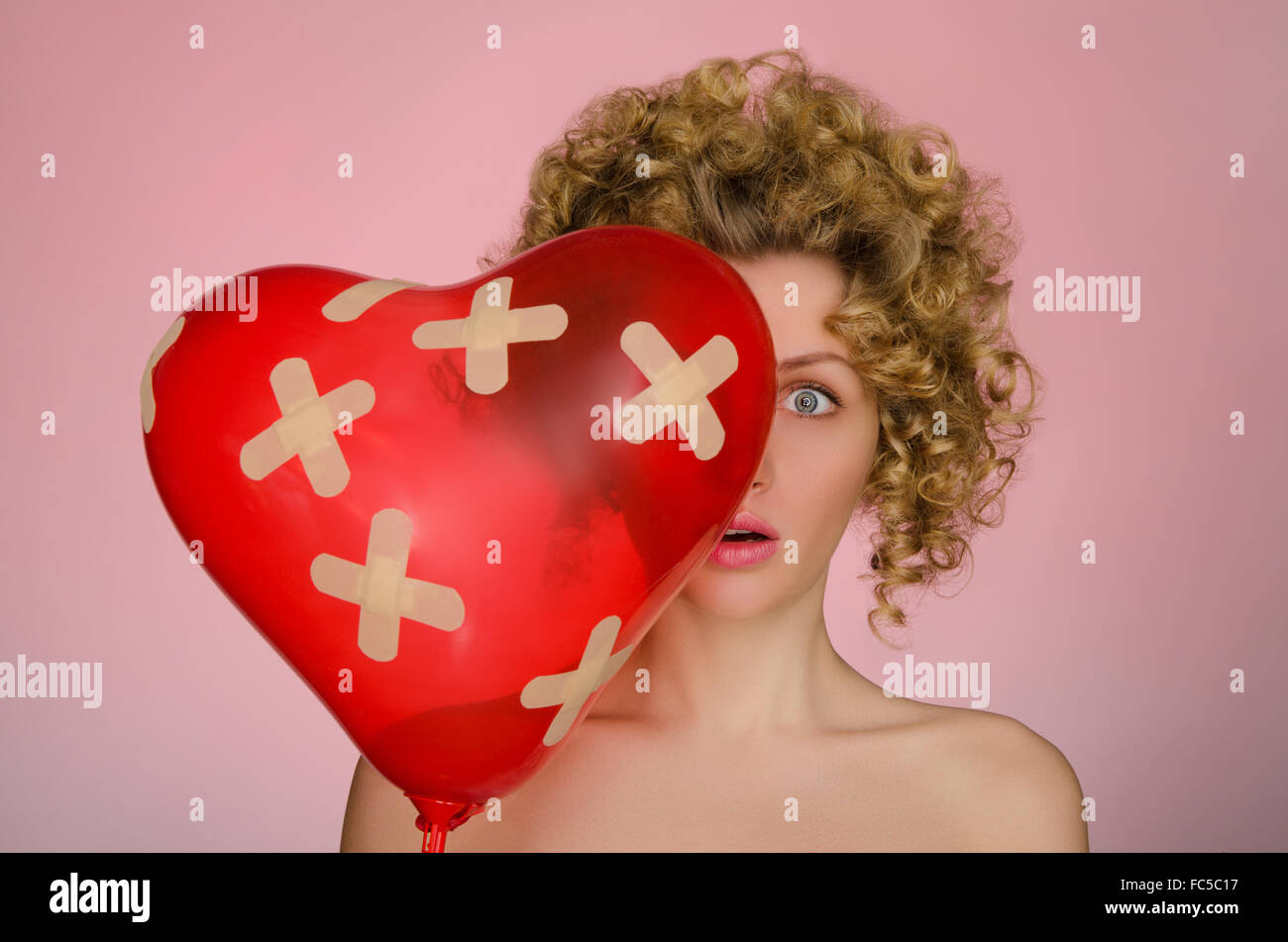 Donna infelice con sfera a forma di cuore Foto Stock