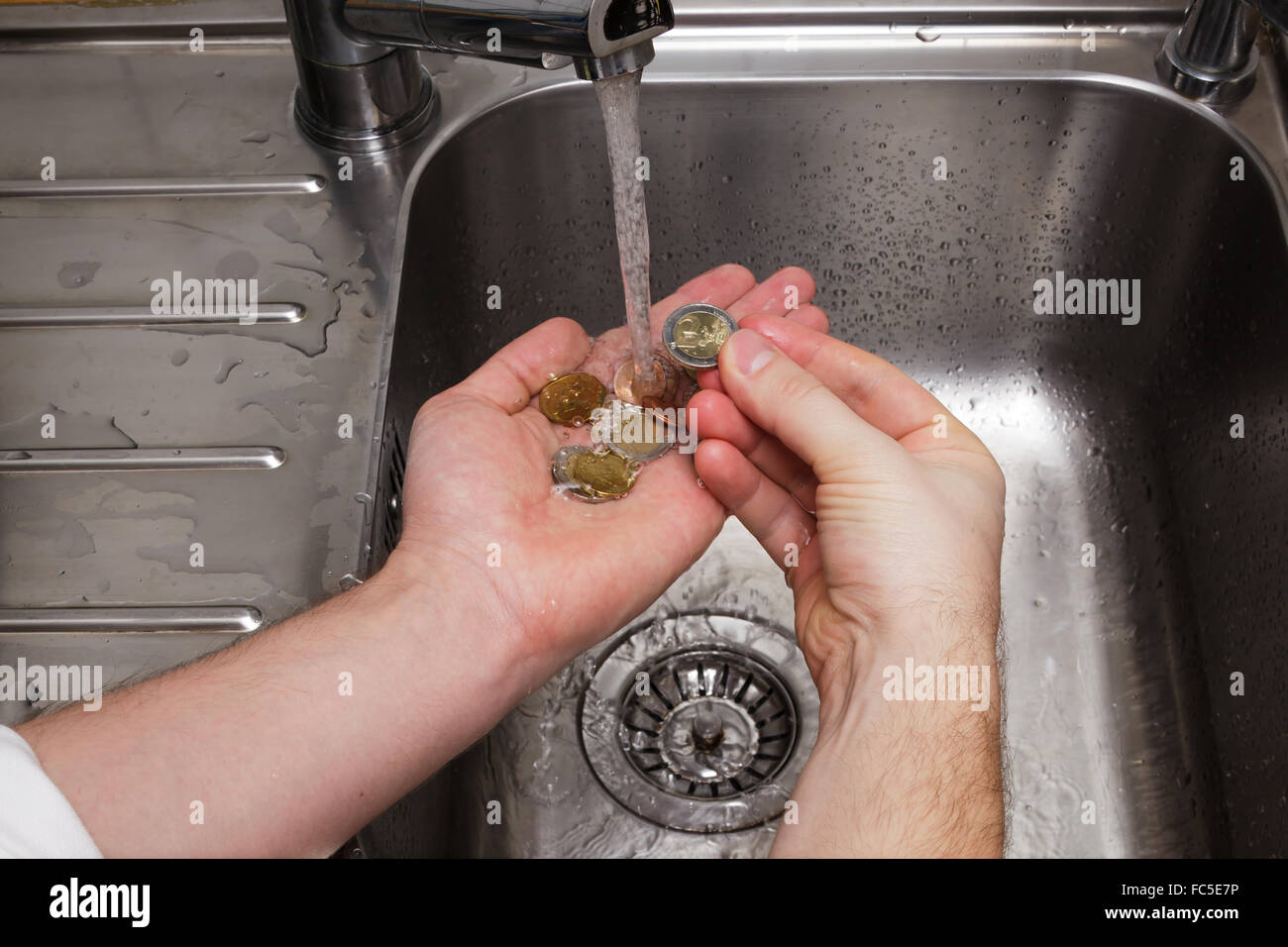 Uomo di monete di lavaggio sotto acqua corrente Foto Stock