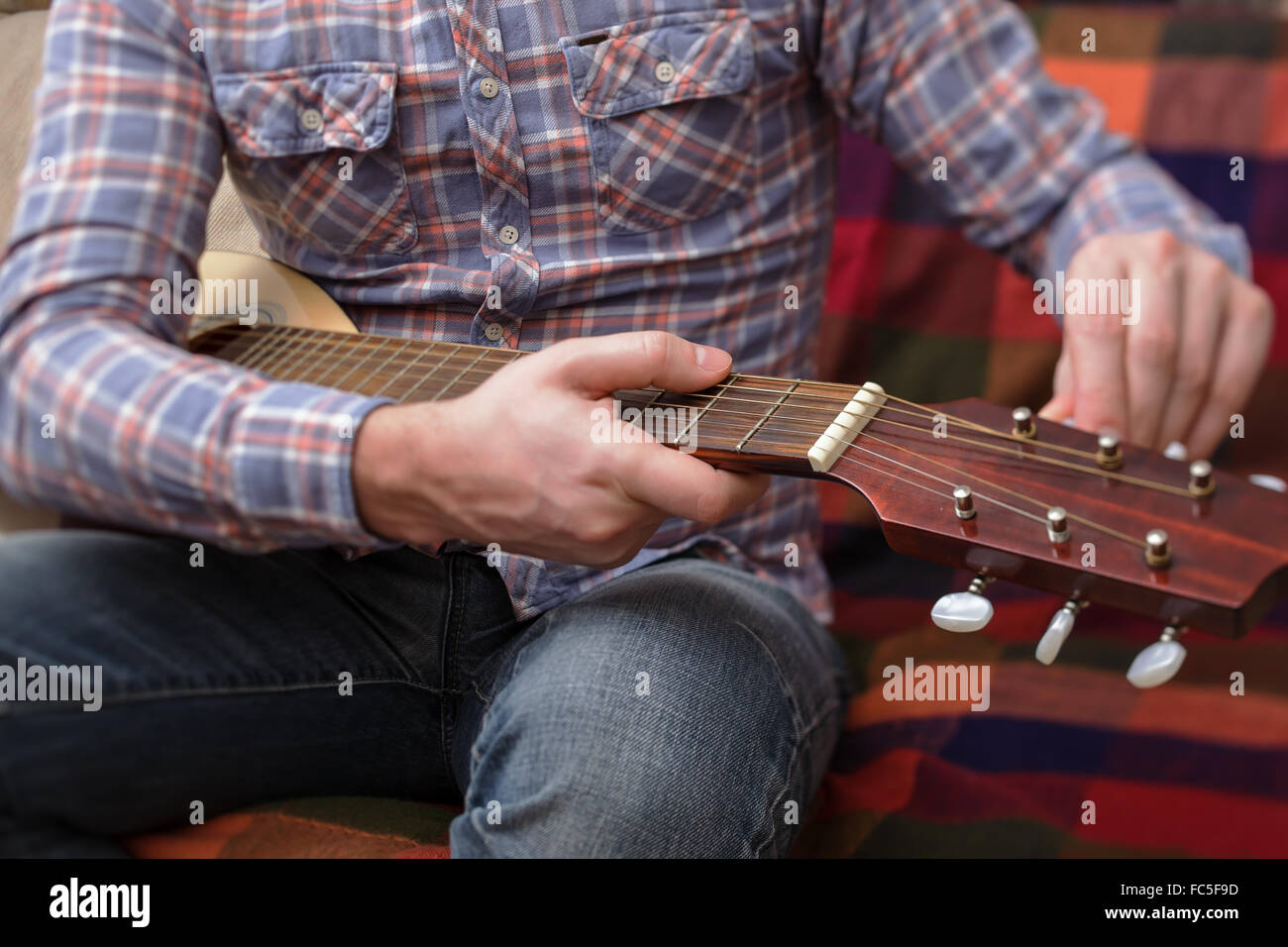 Giovane musicista imposta una piccola chitarra. debug di strumenti musicali Foto Stock