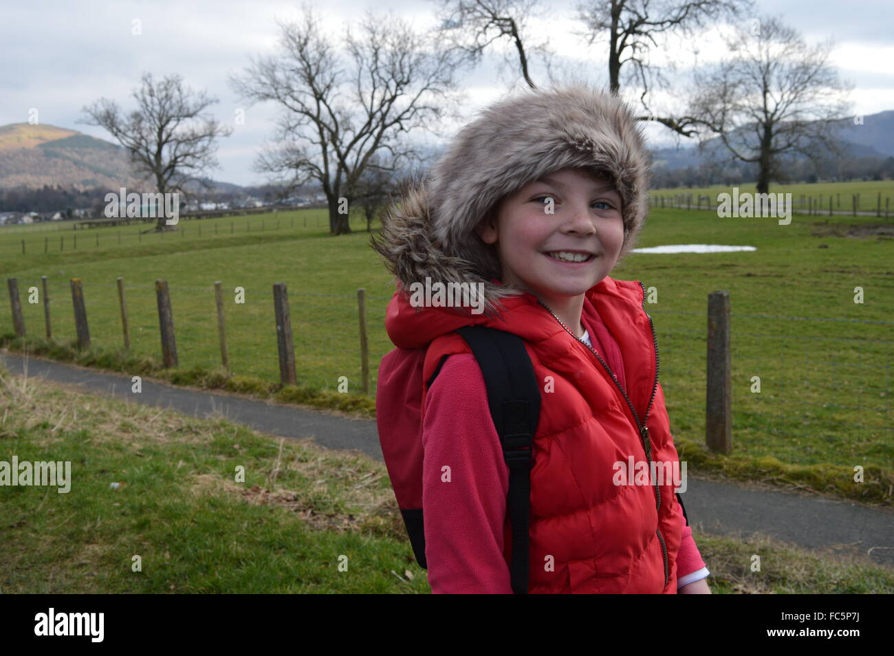 Ragazza in un rivestimento di colore rosso con un cappello di pelliccia e il cofano con uno sfondo di Lake District cumbria Foto Stock