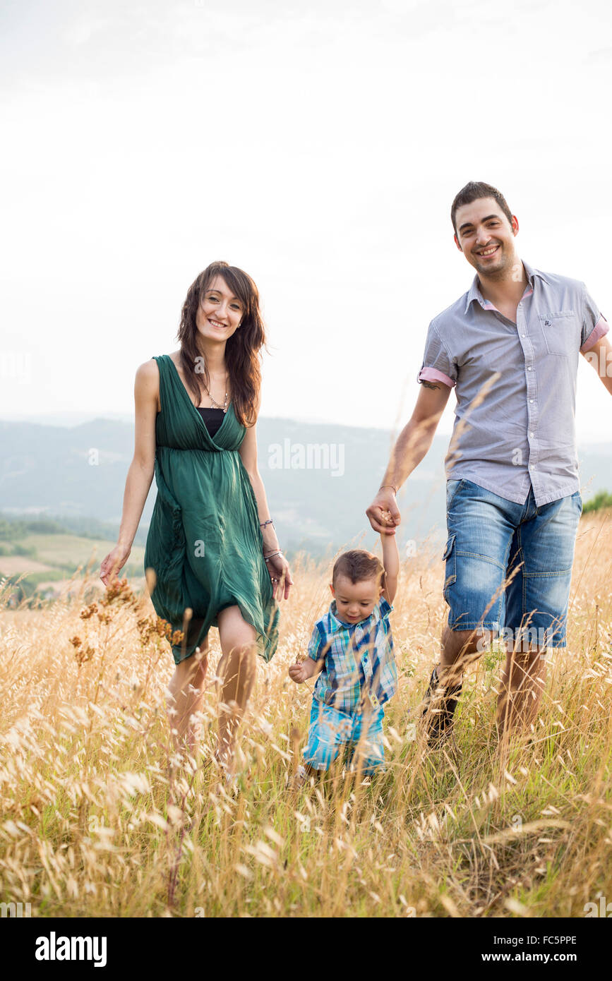 Sorridendo i genitori a piedi con giovane figlio nel campo Foto Stock