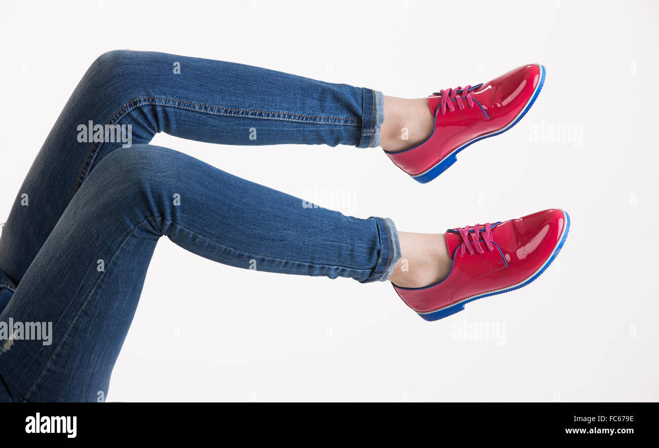 La donna per le gambe in blue jeans e scarpe rosso Foto Stock